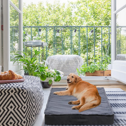 Golden retriever lying on a grey rectangular pet bed in a sunlit room with a balcony view
