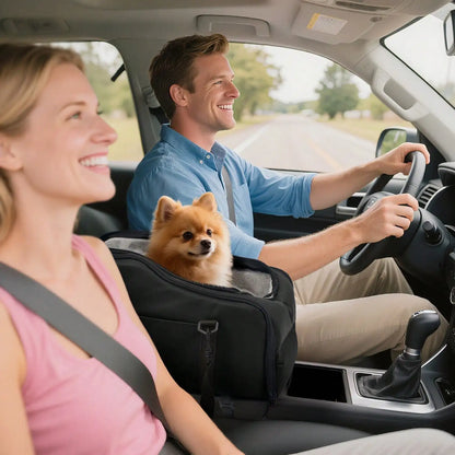 Small dog sitting in a black pet car seat between a man driving and a woman in the passenger seat